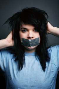 Woman with tape over her mouth and messy dark hair, stock photo